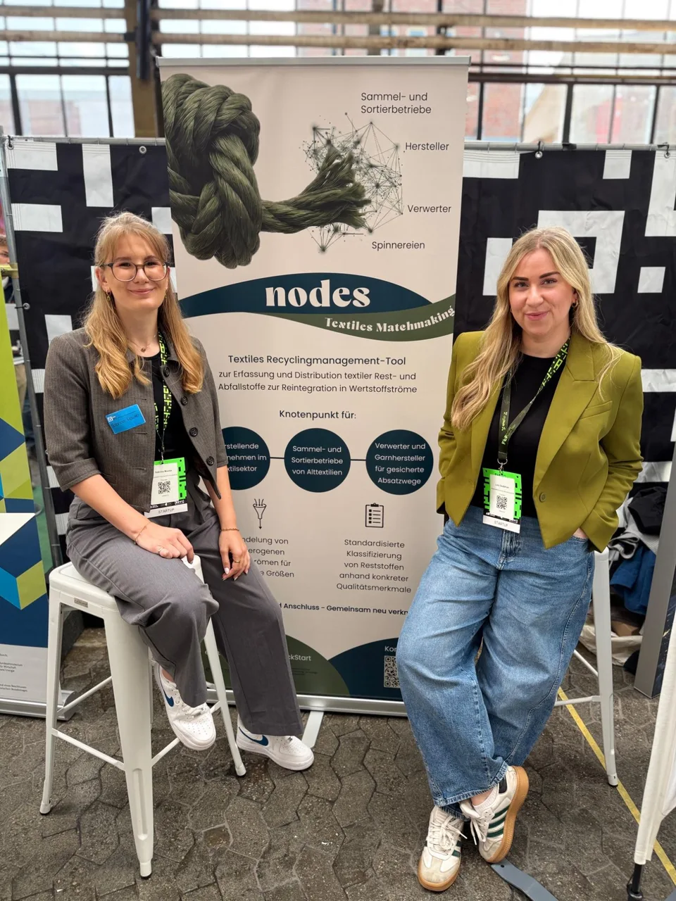 Sabrina Mauter (links) und Lisa Gudehus (rechts) am nodes-Stand auf dem Future Tech Fest 2026, vor dem Roll-up „Textiles Matchmaking“