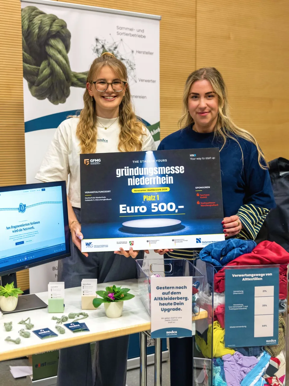 Sabrina Mauter (links) und Lisa Gudehus (rechts) am nodes-Stand auf der Gründungsmesse Niederrhein 2026 mit dem großen Gewinnerscheck „Newcomer Wettbewerb 2026 – Platz 1“